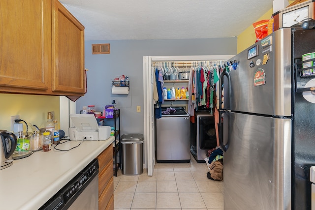 kitchen featuring washer / dryer, a textured ceiling, stainless steel appliances, and light tile patterned floors