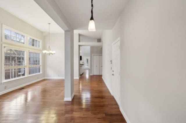 entrance foyer featuring plenty of natural light, dark hardwood / wood-style floors, and a notable chandelier