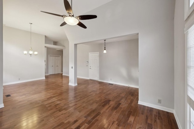 unfurnished living room with dark hardwood / wood-style floors, ceiling fan with notable chandelier, and high vaulted ceiling