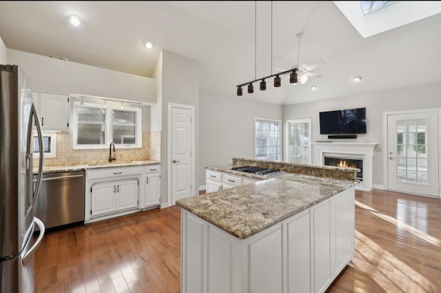 kitchen featuring white cabinetry, stainless steel appliances, light stone counters, dark hardwood / wood-style floors, and a kitchen island