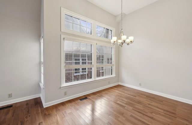 unfurnished dining area with a wealth of natural light, hardwood / wood-style floors, and a chandelier