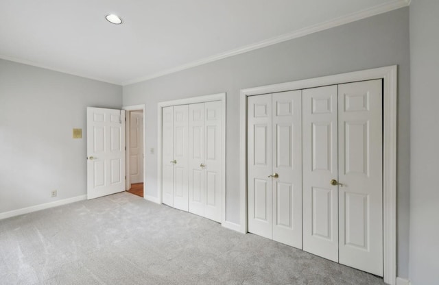 unfurnished bedroom with light carpet, two closets, and ornamental molding