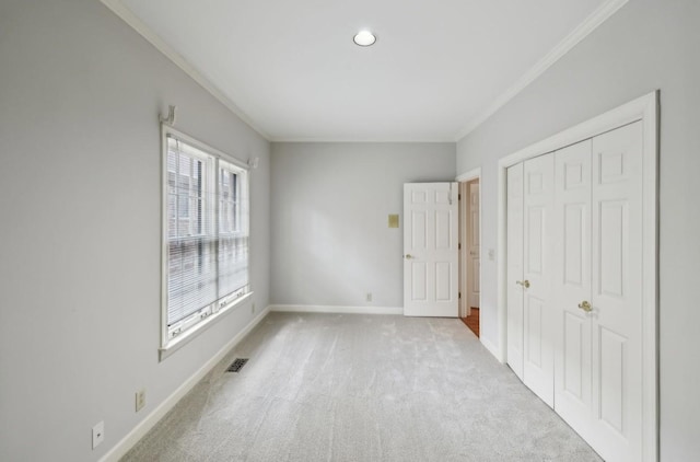 unfurnished bedroom featuring light colored carpet, a closet, and ornamental molding