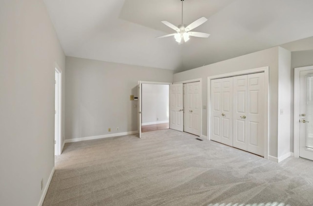 unfurnished bedroom featuring light carpet, ceiling fan, and multiple closets