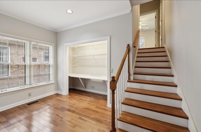 stairway featuring wood-type flooring and ornamental molding