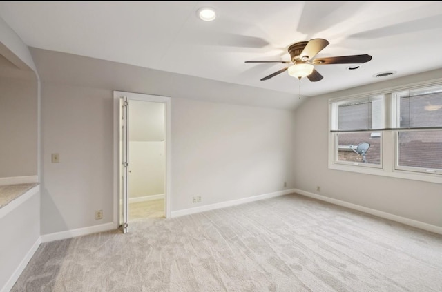 carpeted spare room with ceiling fan and vaulted ceiling