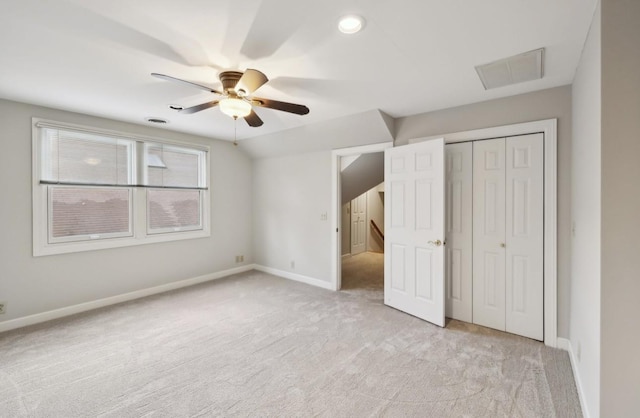 unfurnished bedroom featuring a closet, light colored carpet, and ceiling fan