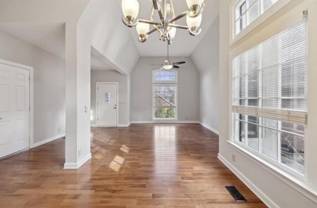 unfurnished living room featuring ceiling fan with notable chandelier, hardwood / wood-style flooring, and vaulted ceiling