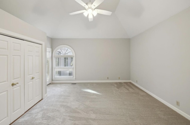 unfurnished bedroom with ceiling fan, a closet, light colored carpet, and vaulted ceiling