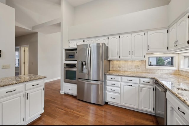 kitchen with decorative backsplash, appliances with stainless steel finishes, light stone countertops, dark wood-type flooring, and white cabinets