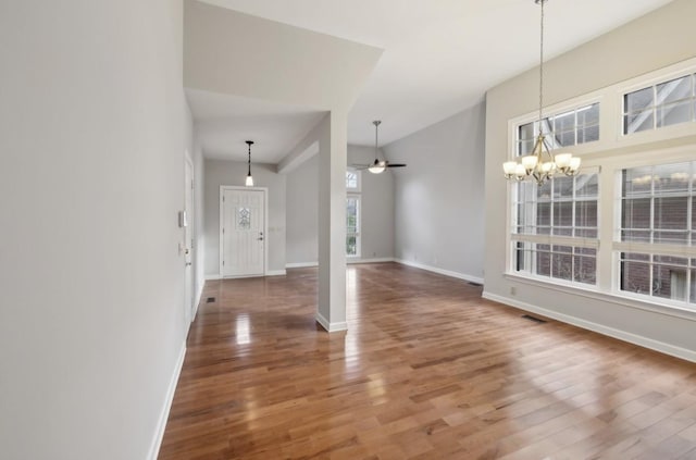 foyer entrance with hardwood / wood-style floors and ceiling fan with notable chandelier