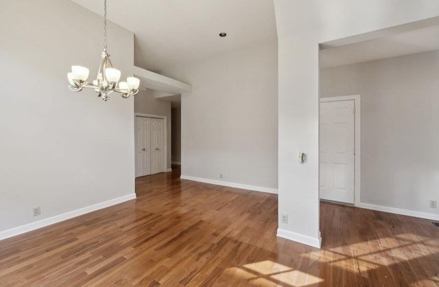 empty room featuring hardwood / wood-style floors, a notable chandelier, and a high ceiling