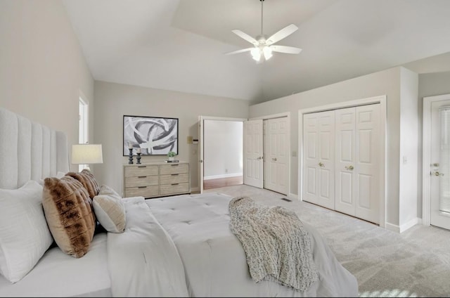 bedroom with two closets, vaulted ceiling, ceiling fan, and light colored carpet