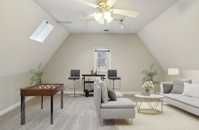 interior space featuring vaulted ceiling with skylight, ceiling fan, and light colored carpet