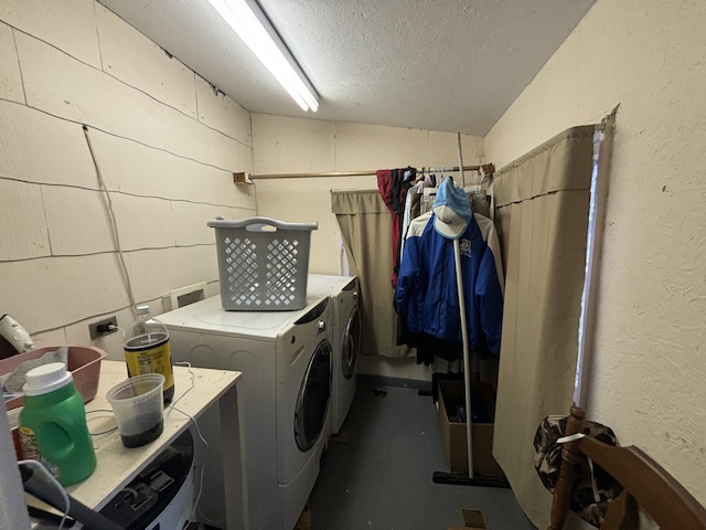 clothes washing area with a textured ceiling and washer and clothes dryer