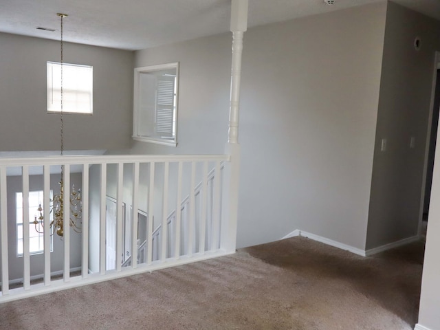 carpeted spare room featuring a notable chandelier