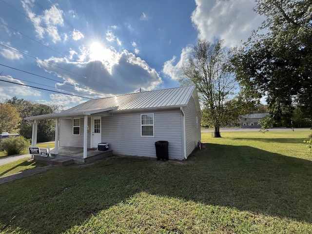 back of property with a yard, a porch, and metal roof