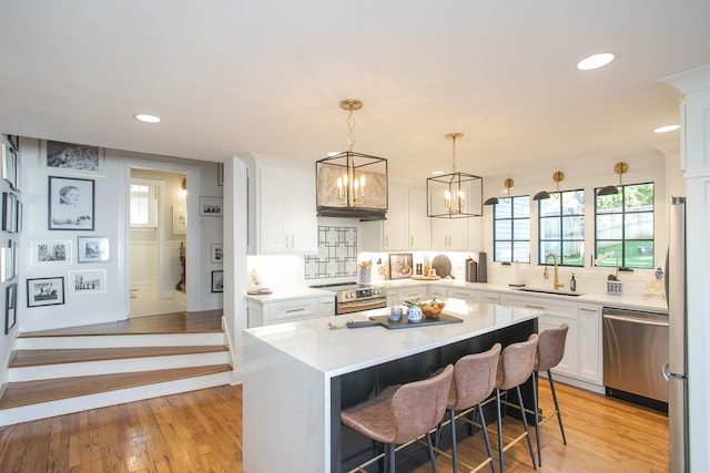 kitchen featuring light hardwood / wood-style floors, a kitchen island, decorative backsplash, white cabinetry, and stainless steel appliances