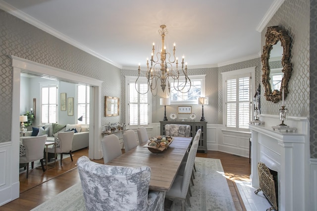 dining area featuring dark wood-type flooring, ornamental molding, and a notable chandelier