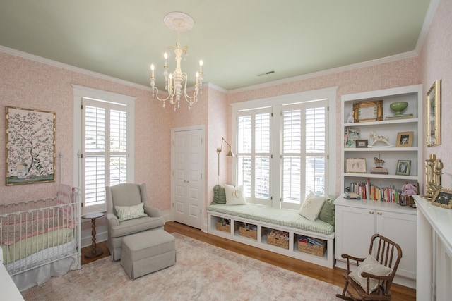 sitting room featuring light wood-type flooring, an inviting chandelier, and crown molding