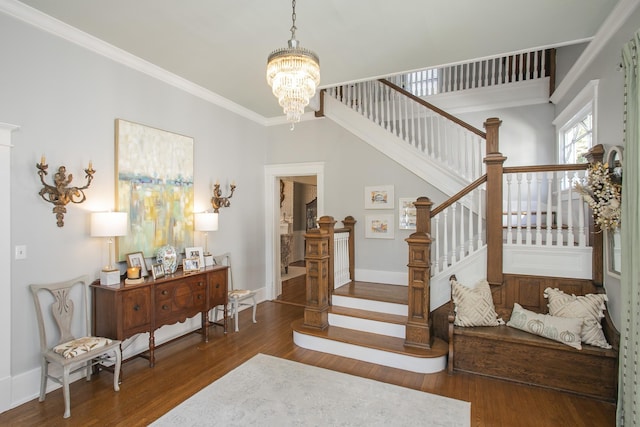 stairs with hardwood / wood-style flooring, ornamental molding, and an inviting chandelier