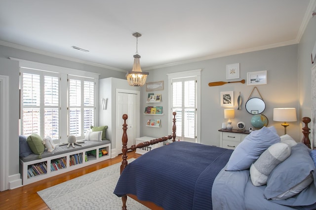 bedroom with hardwood / wood-style floors, a closet, crown molding, and an inviting chandelier