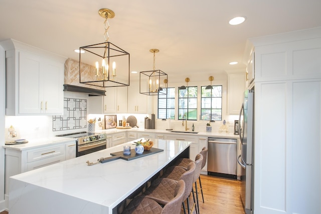 kitchen with a kitchen island, sink, white cabinetry, light stone countertops, and appliances with stainless steel finishes