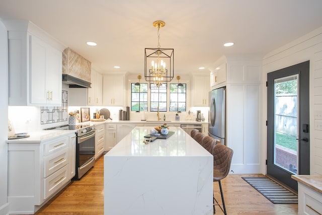 kitchen featuring light hardwood / wood-style flooring, a kitchen island, stainless steel appliances, and white cabinetry