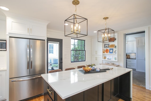 kitchen featuring light stone countertops, white cabinets, appliances with stainless steel finishes, and light hardwood / wood-style flooring