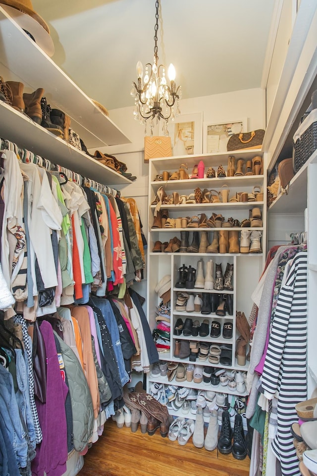 walk in closet with a chandelier and hardwood / wood-style floors