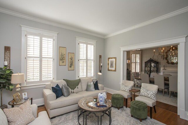 living room featuring wood-type flooring, plenty of natural light, ornamental molding, and a notable chandelier