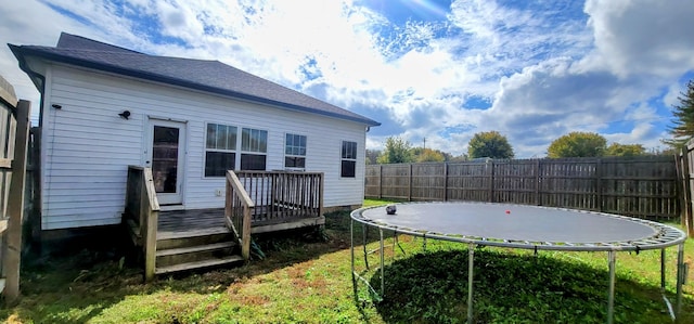 back of property with a trampoline and a wooden deck