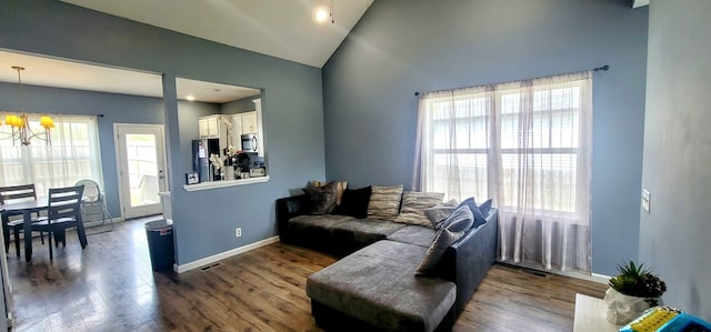 living room featuring dark hardwood / wood-style flooring, high vaulted ceiling, and an inviting chandelier