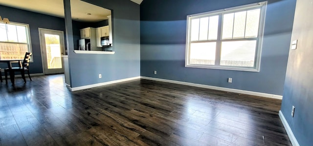 empty room featuring plenty of natural light and dark wood-type flooring