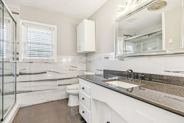 bathroom featuring a shower with door, toilet, tile patterned flooring, tile walls, and vanity