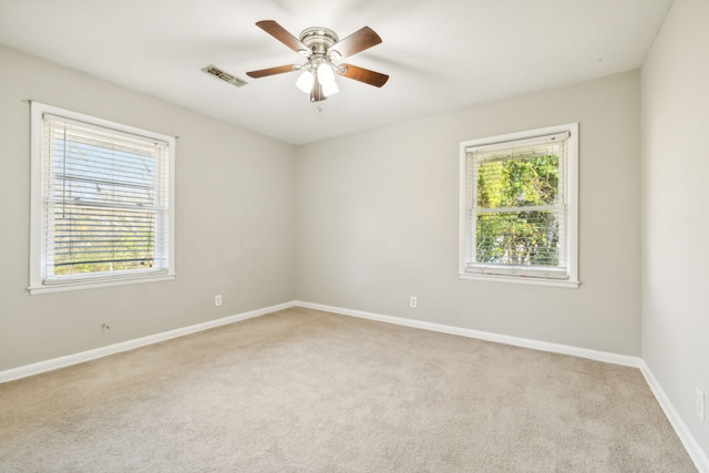 carpeted spare room with a healthy amount of sunlight and ceiling fan