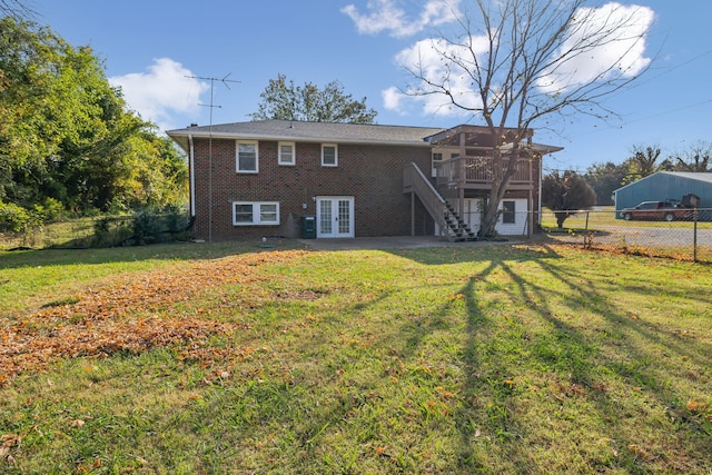 rear view of property featuring a wooden deck, a lawn, and french doors