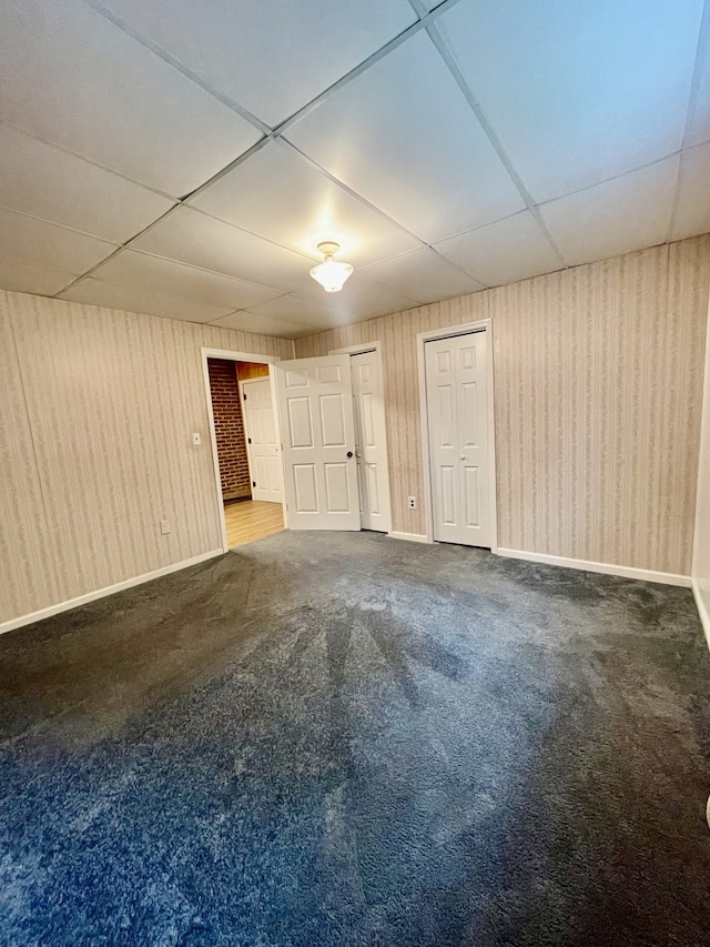 basement featuring a paneled ceiling and carpet