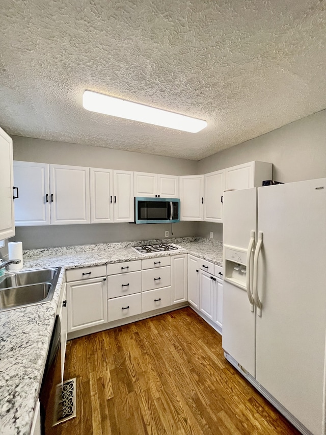 kitchen featuring white cabinetry, a textured ceiling, light hardwood / wood-style flooring, sink, and white appliances