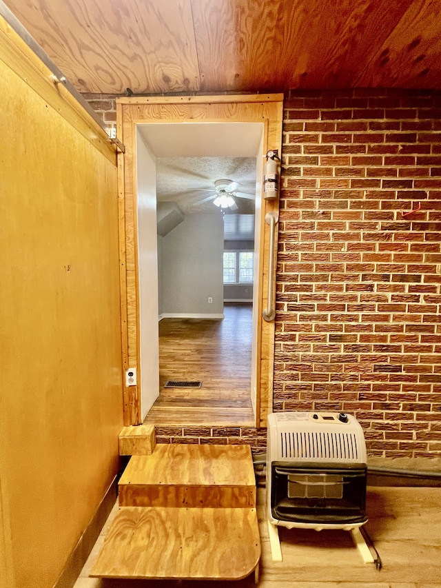 hall featuring brick wall, hardwood / wood-style floors, and heating unit