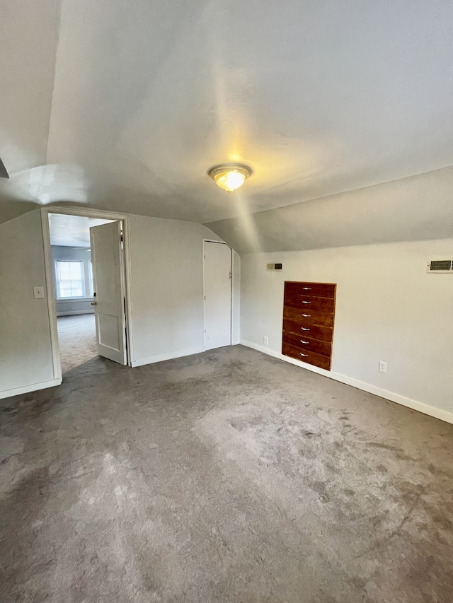 additional living space featuring dark carpet and vaulted ceiling