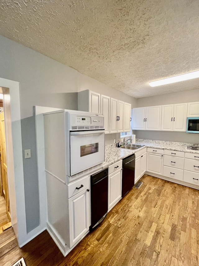 kitchen with light hardwood / wood-style flooring, white cabinetry, sink, and white appliances