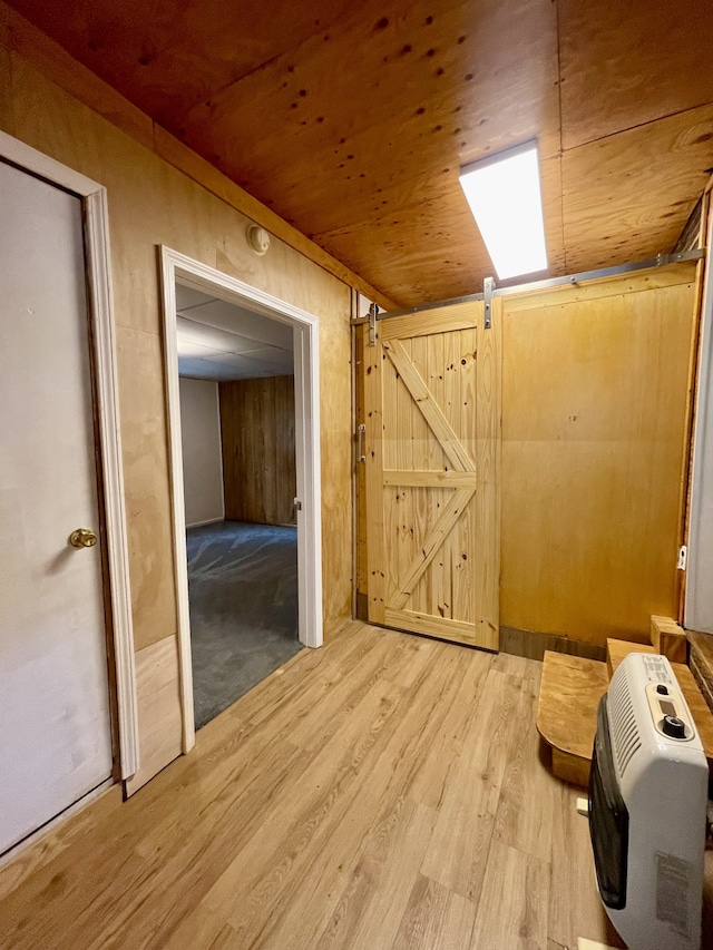 interior space with light hardwood / wood-style floors, wood ceiling, wooden walls, and heating unit