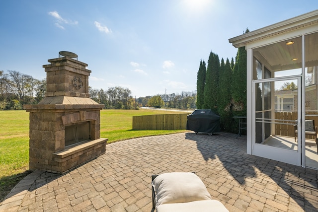 view of patio featuring an outdoor stone fireplace and a grill