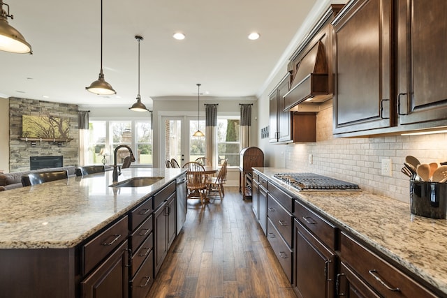 kitchen featuring ornamental molding, stainless steel appliances, sink, dark hardwood / wood-style floors, and an island with sink