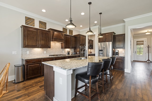 kitchen with sink, hanging light fixtures, dark hardwood / wood-style floors, an island with sink, and stainless steel appliances