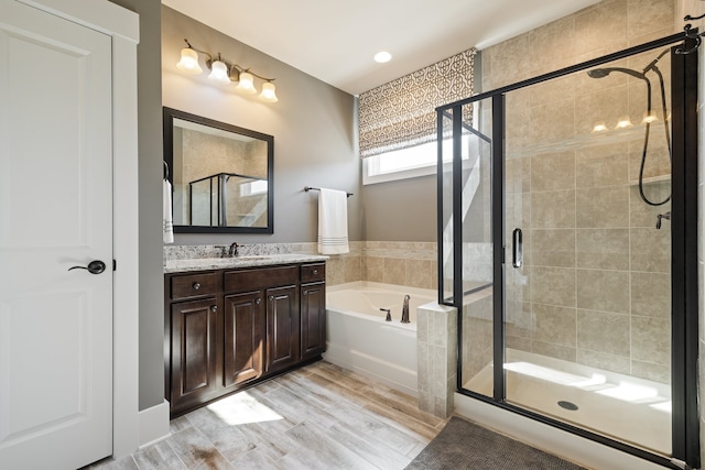 bathroom featuring vanity, wood-type flooring, and shower with separate bathtub