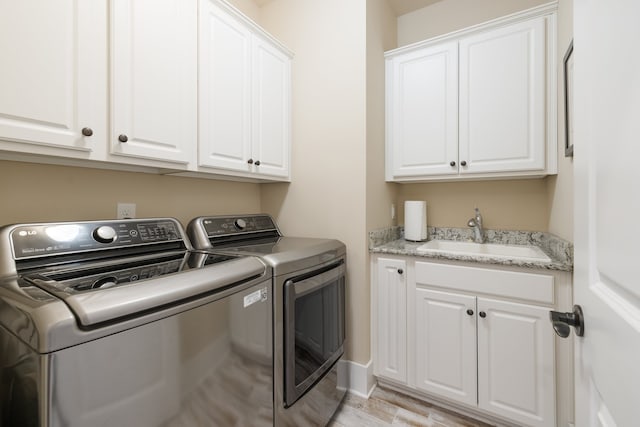 washroom featuring washer and clothes dryer, cabinets, sink, and light hardwood / wood-style flooring