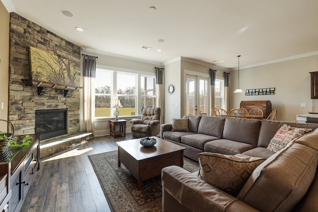 living room with dark hardwood / wood-style floors, a stone fireplace, and ornamental molding