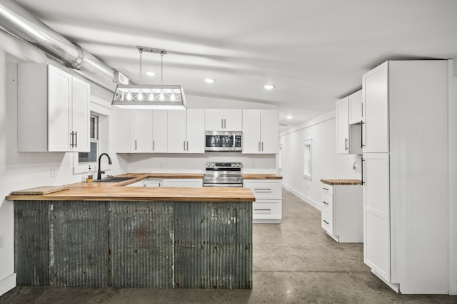 kitchen with kitchen peninsula, appliances with stainless steel finishes, white cabinetry, vaulted ceiling, and sink